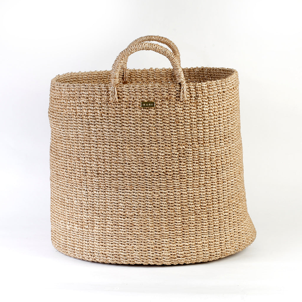 Camille Round Basket Hamper made from 100% natural plant fiber, featuring a beautifully woven design that adds rustic charm and eco-friendly storage to any room. Ideal for organizing laundry, toys, throw pillows, and bath essentials, while also enhancing home decor with indoor plants. Care instructions recommend avoiding prolonged water exposure and using spot cleaning for maintenance.