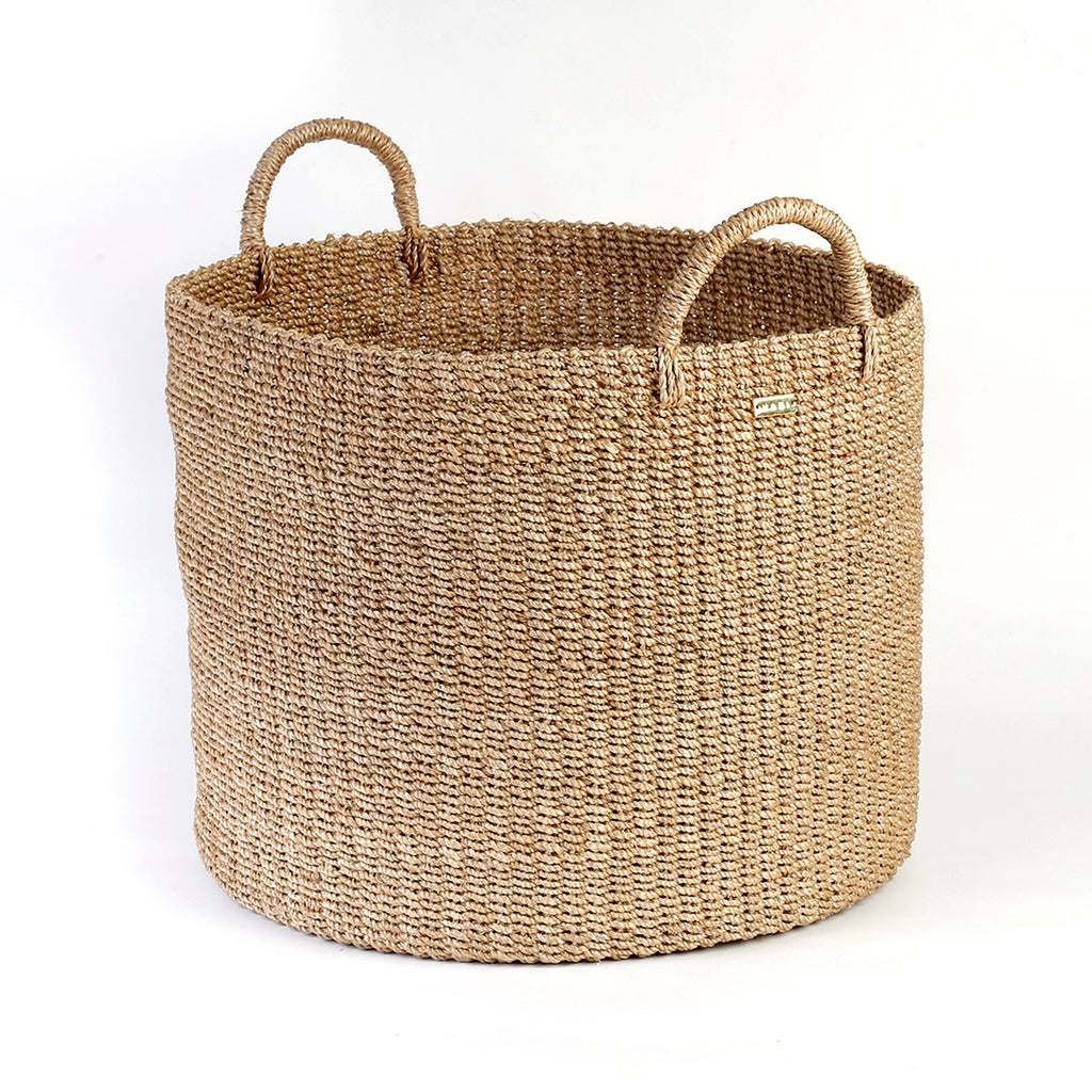 Camille Round Basket Hamper made from 100% natural plant fiber, featuring a beautifully woven design that adds rustic charm and eco-friendly storage to any room. Ideal for organizing laundry, toys, throw pillows, and bath essentials, while also enhancing home decor with indoor plants. Care instructions recommend avoiding prolonged water exposure and using spot cleaning for maintenance.