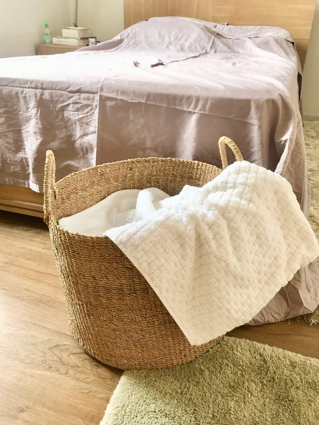 Camille Round Basket Hamper made from 100% natural plant fiber, featuring a beautifully woven design that adds rustic charm and eco-friendly storage to any room. Ideal for organizing laundry, toys, throw pillows, and bath essentials, while also enhancing home decor with indoor plants. Care instructions recommend avoiding prolonged water exposure and using spot cleaning for maintenance.
