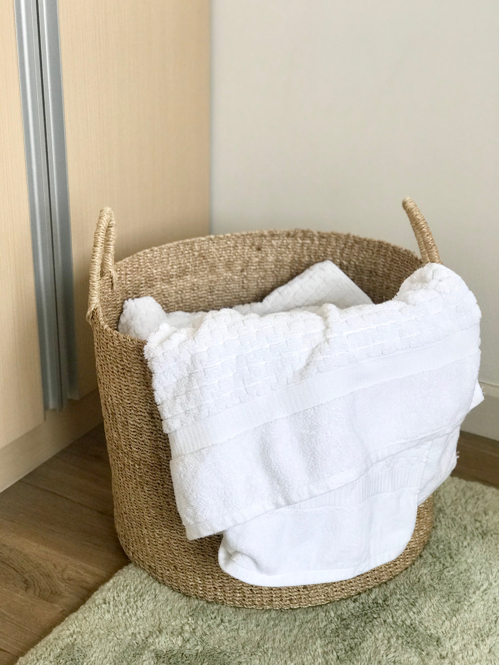 Camille Round Basket Hamper made from 100% natural plant fiber, featuring a beautifully woven design that adds rustic charm and eco-friendly storage to any room. Ideal for organizing laundry, toys, throw pillows, and bath essentials, while also enhancing home decor with indoor plants. Care instructions recommend avoiding prolonged water exposure and using spot cleaning for maintenance.