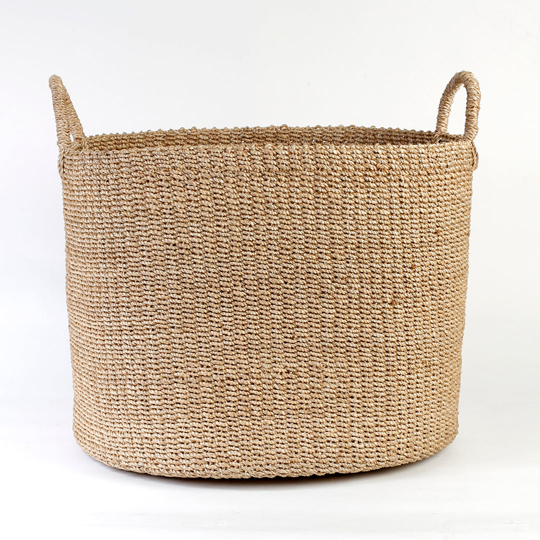 Camille Round Basket Hamper made from 100% natural plant fiber, featuring a beautifully woven design that adds rustic charm and eco-friendly storage to any room. Ideal for organizing laundry, toys, throw pillows, and bath essentials, while also enhancing home decor with indoor plants. Care instructions recommend avoiding prolonged water exposure and using spot cleaning for maintenance.